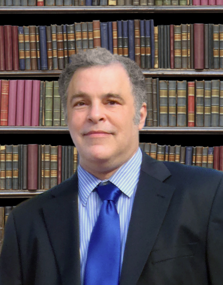 Richard Lewis smiling in front of a legal library.